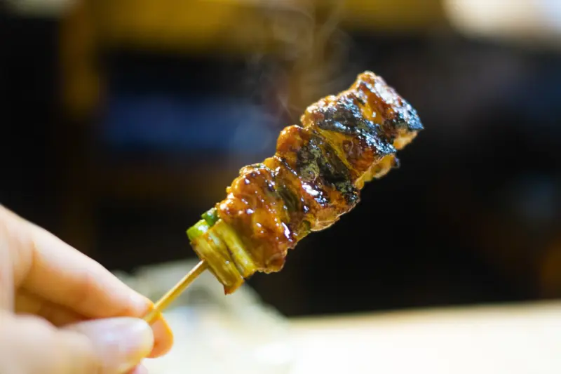  A chef grilling yakitori skewers over a charcoal flame
