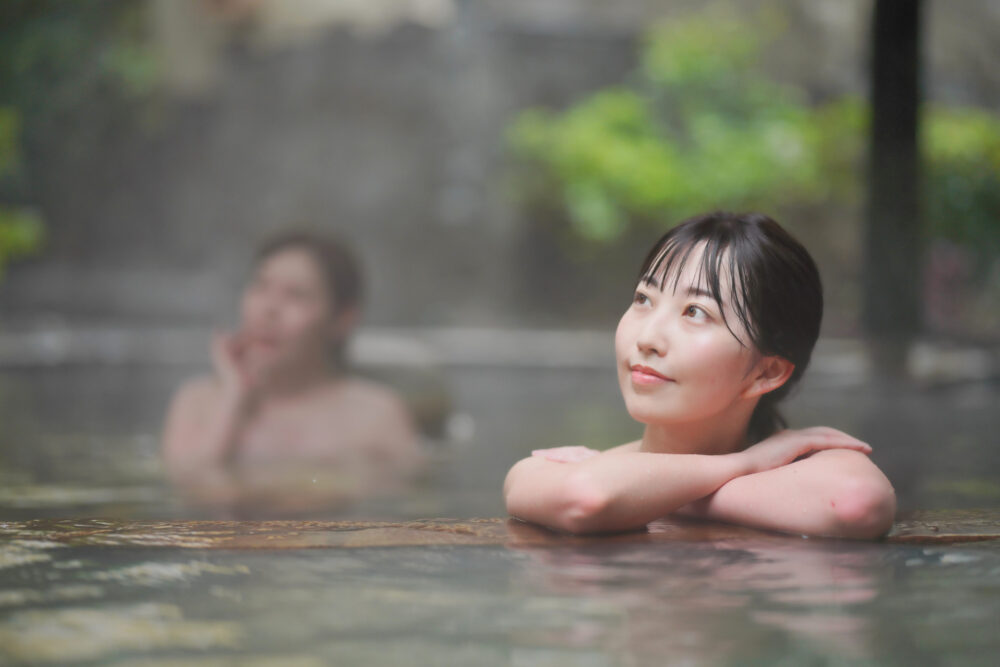 A woman relaxing in an onsen, submerged up to her shoulders in the warm water.