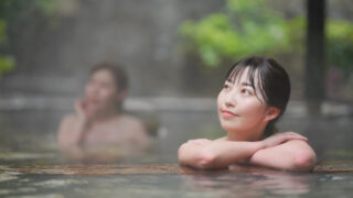 A woman relaxing in an onsen, submerged up to her shoulders in the warm water.