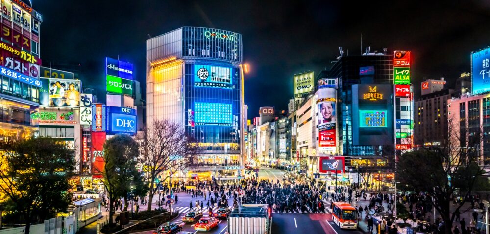 Night view of tokyo Shibuya Crossing with neon-lit buildings.
