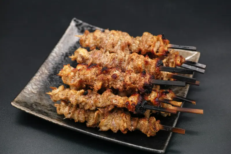 Crispy chicken skin skewers on a wooden plate
