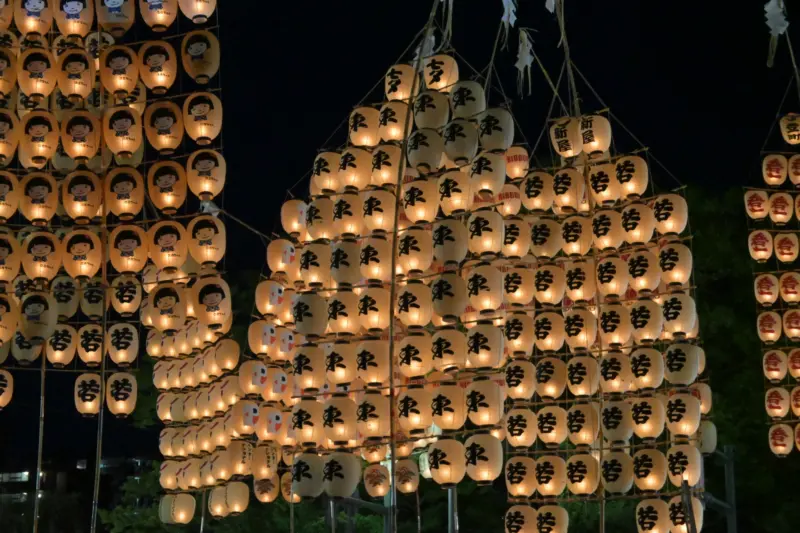 Performers balancing tall bamboo poles with lanterns at the Akita Kanto Festival