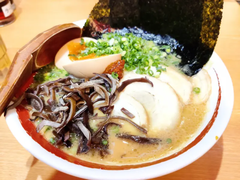 A steaming bowl of Hakata ramen, featuring pork bone broth