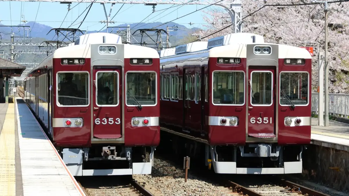 A Hankyu Arashiyama Line train traveling through the scenic countryside near Arashiyama.