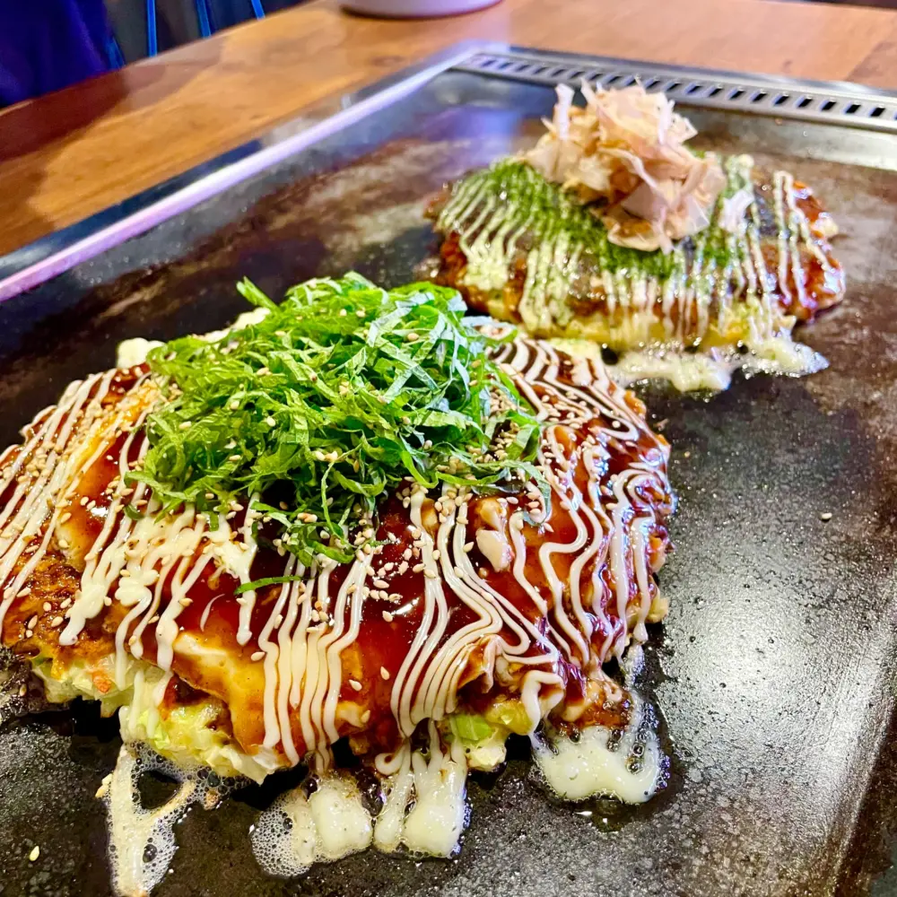 Okonomiyaki being prepared on a griddle