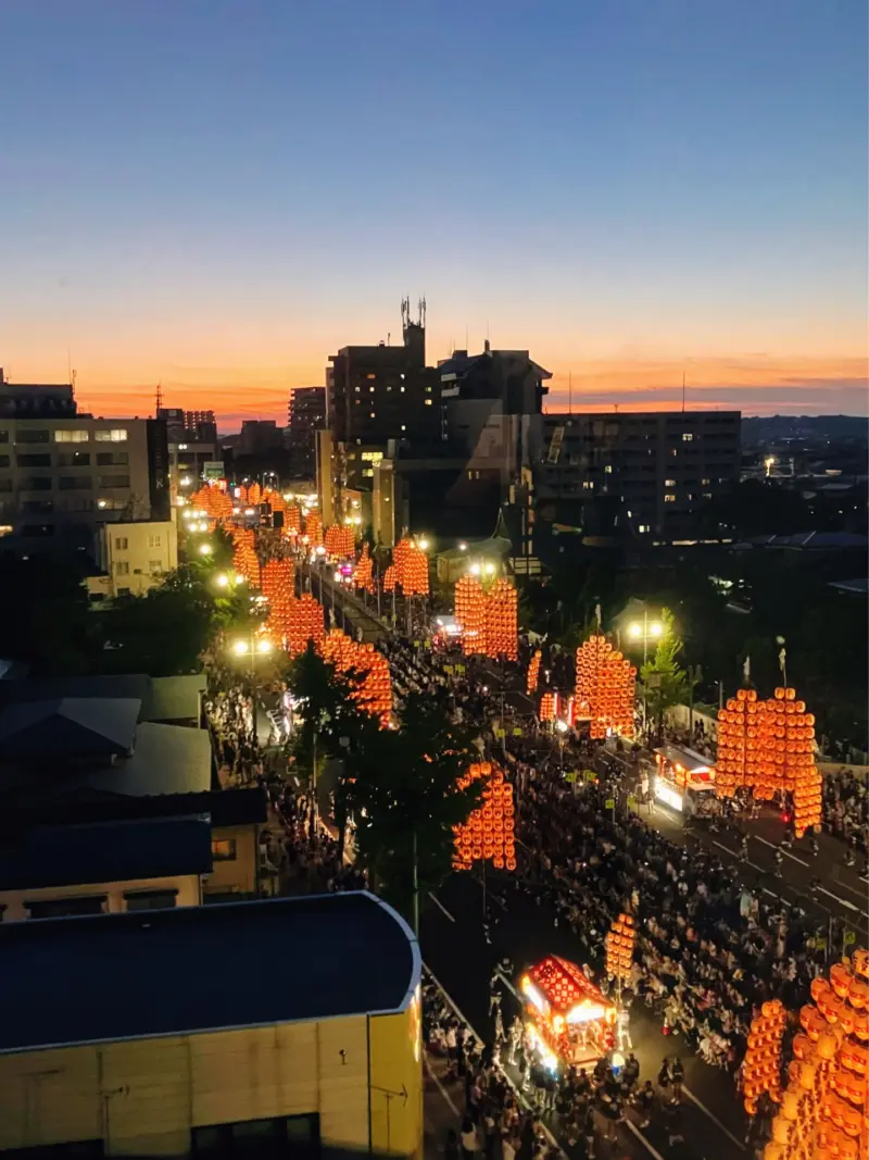 Performers balancing tall bamboo poles with lanterns at the Akita Kanto Festival