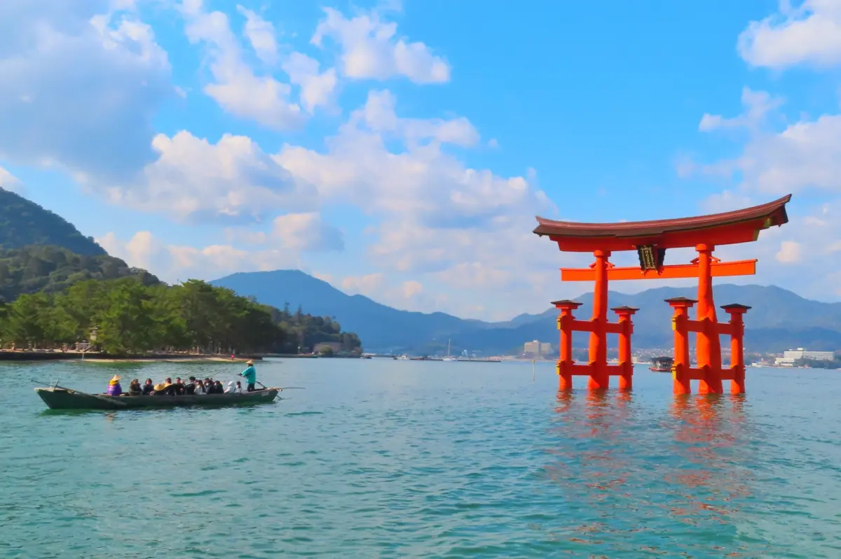 Tourists at Itsukushima Shrine with the famous floating Torii gate during high tide.
