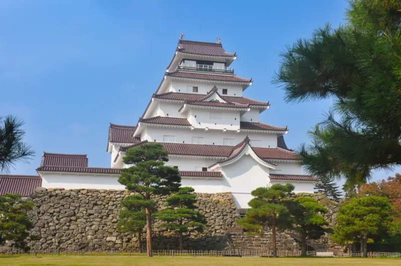 Tsuruga Castle with its iconic red roof and surrounding cherry blossoms