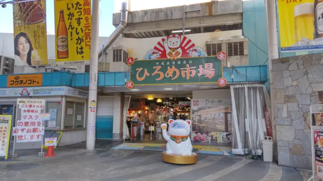 A bustling Hirome Market in Kochi City, showcasing fresh seafood and local dishes like katsuo no tataki.