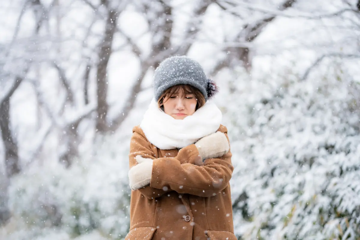 Woman shivering in the snow, dressed for winter in Japan's cold weather.