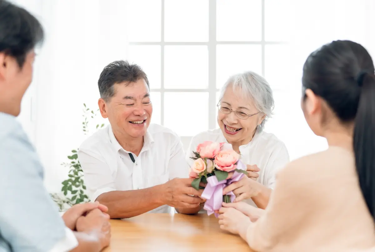 A son and his wife presenting flowers to their parents on Respect for the Aged Day, a Japanese holiday honoring older generations.