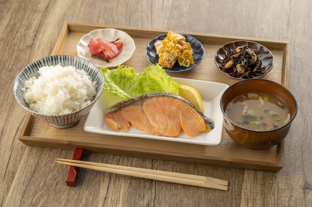 A traditional Japanese breakfast featuring grilled salmon, miso soup, and rice.