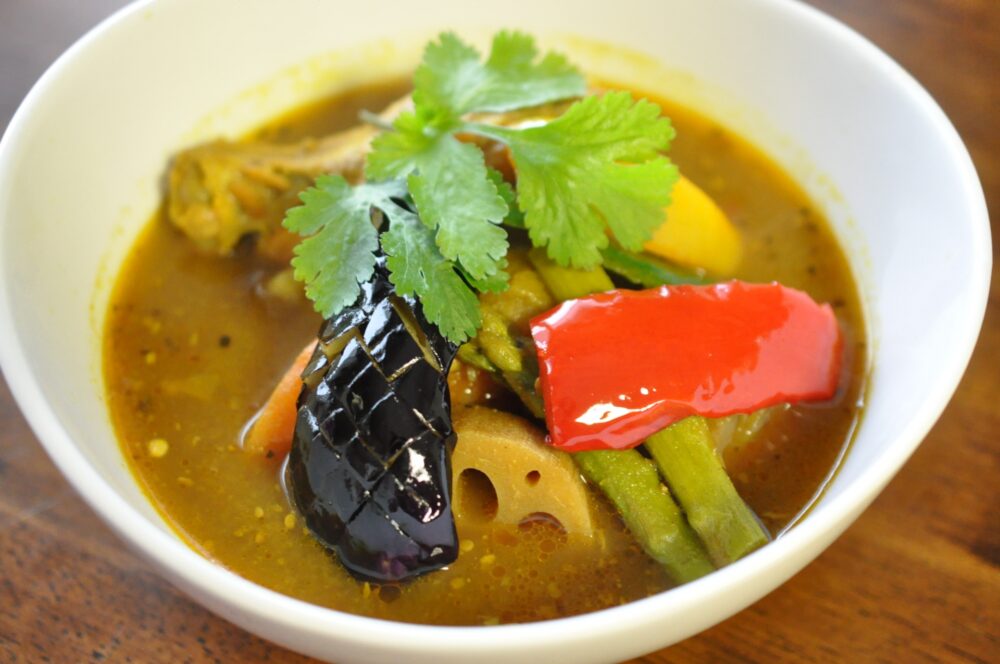 A bowl of soup curry Hokkaido topped with an assortment of fresh vegetables.