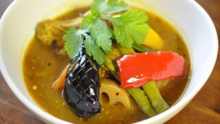 A bowl of soup curry Hokkaido topped with an assortment of fresh vegetables.