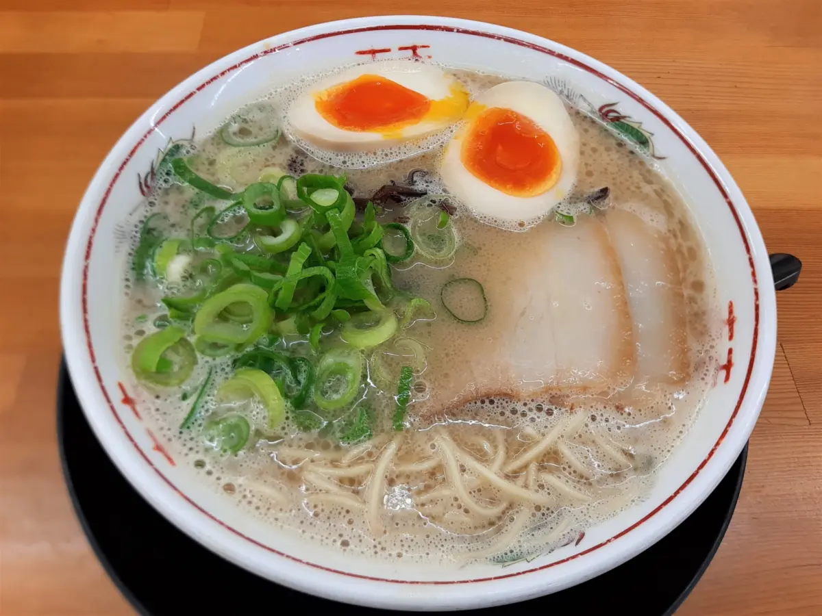 A steaming bowl of tonkotsu ramen garnished with green onions and nori.