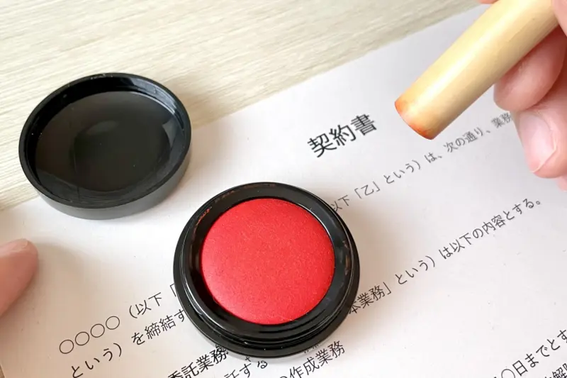  A close-up of a hanko being used to stamp a document.