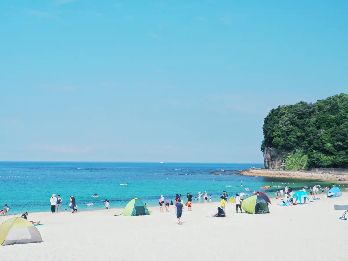 People enjoying a day at the beach, swimming and relaxing under the summer sun in Japan.