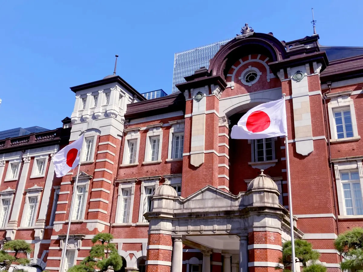 The Japanese national flag fluttering in the wind in front of Tokyo Station.