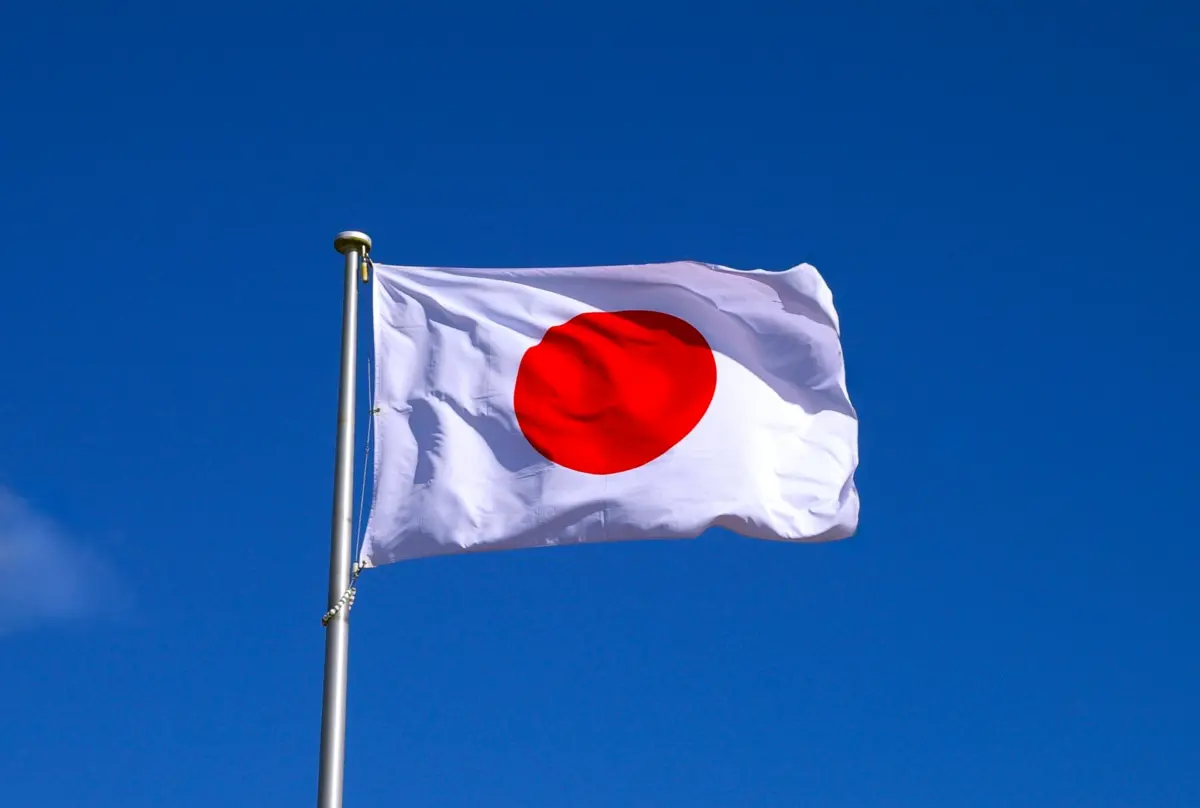 The Japanese national flag, Hinomaru, fluttering against a clear blue sky.