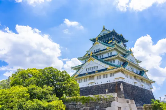 The iconic Osaka Castle surrounded by lush greenery and a tranquil moat.