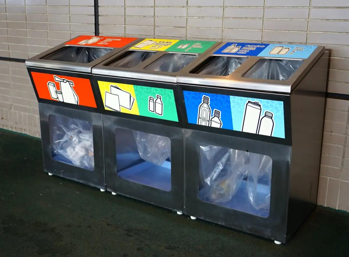 Recycling bins at a train station, labeled for proper waste separation in Japan.