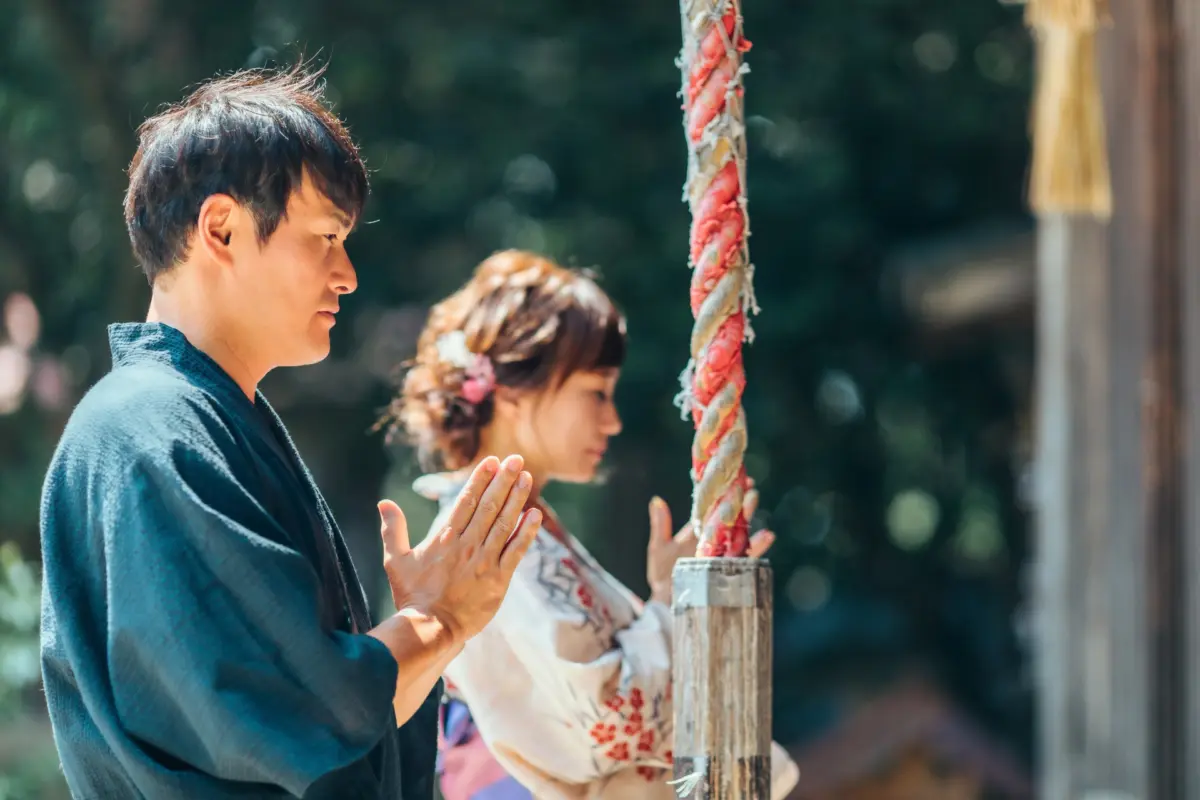 A woman respectfully praying at a Shinto shrine, demonstrating traditional Japanese customs.