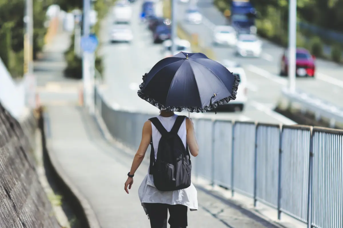 Woman holding a parasol on a sunny day, showcasing Japan's weather and sun protection customs.