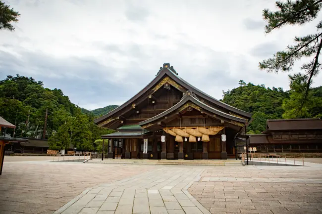 The grand main hall of Izumo Taisha Shrine surrounded by sacred pine trees in Shimane