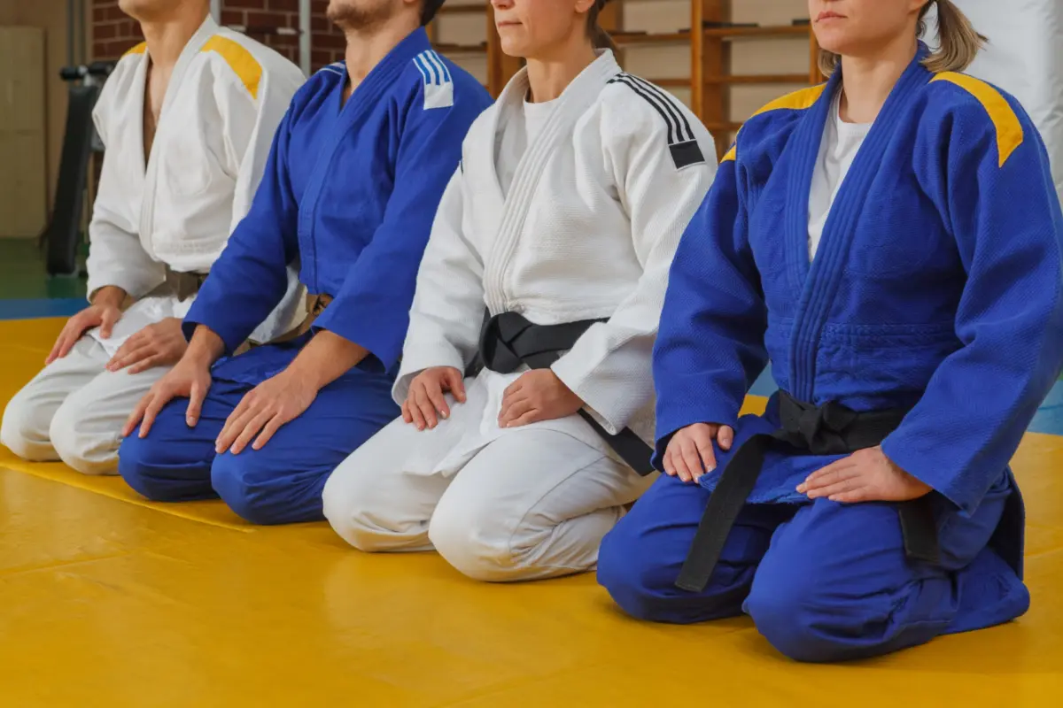 Judo players practicing techniques on soft tatami mats in a traditional dojo.