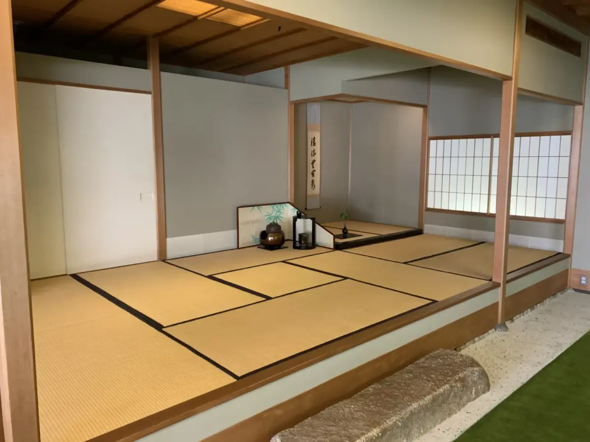 A traditional Japanese tatami room with shoji doors and a tokonoma alcove displaying a flower arrangement