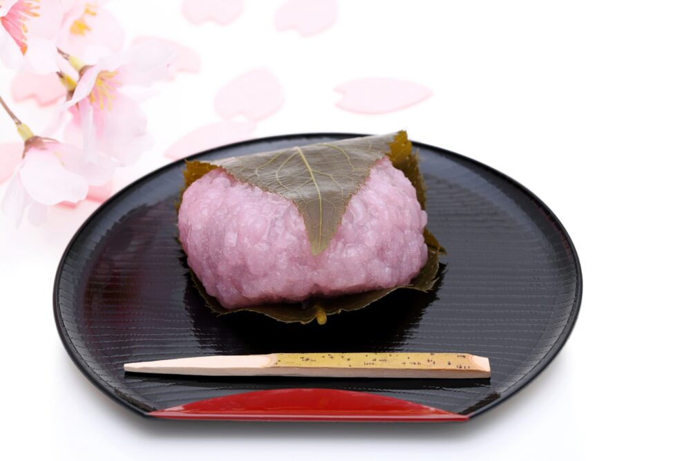 A pink, rice cake wagashi wrapped in a cherry blossom leaf.