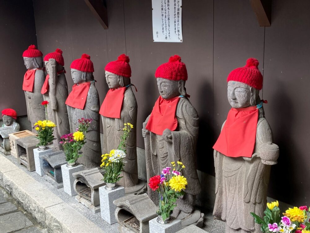 Small Jizo statues dressed in red, lined up at a Japanese temple.