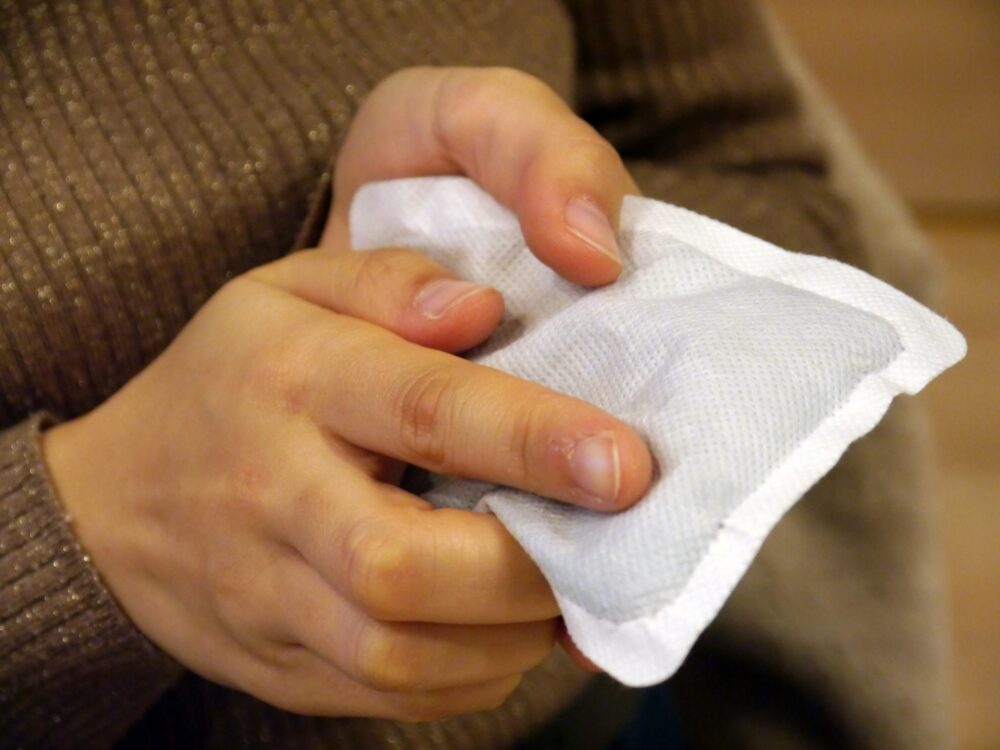 A hand holding a disposable body warmer.