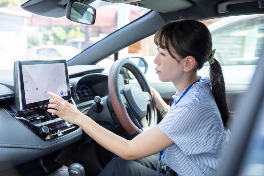 A car dashboard displaying a GPS navigation screen, a Japanese invention.