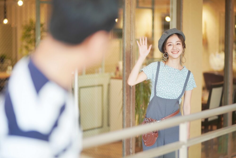 A Japanese person using a downward-facing hand gesture to call someone over.