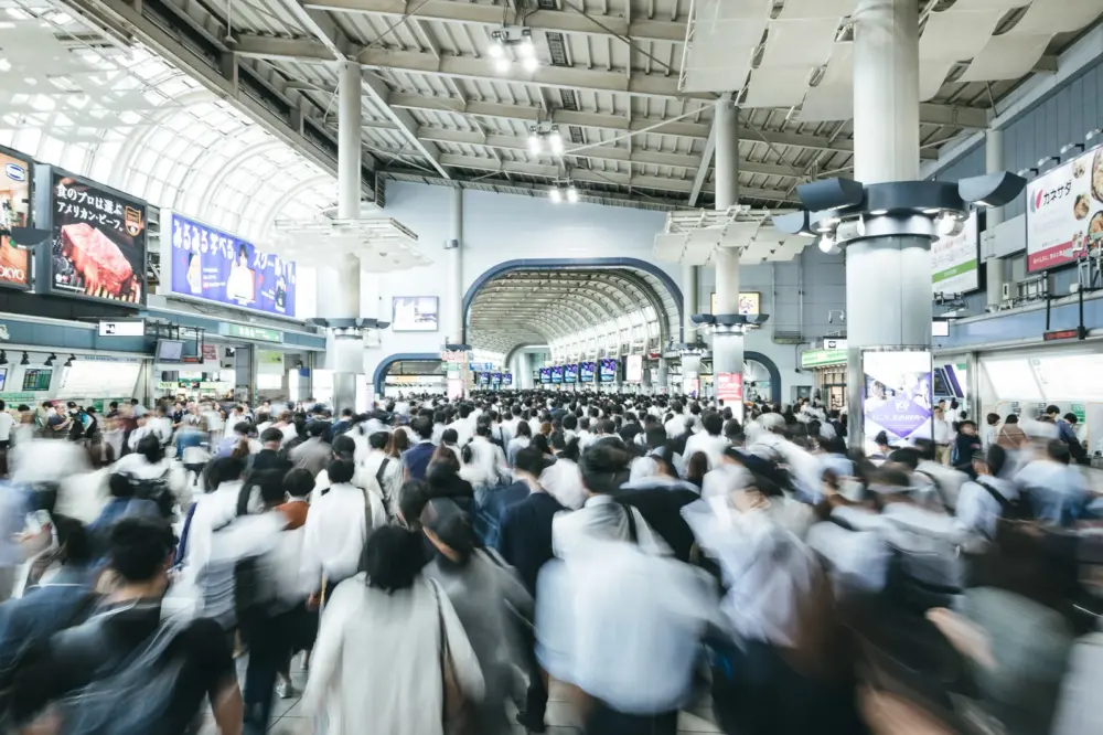 A group of commuters standing in a neat line while waiting for a train in Japan.